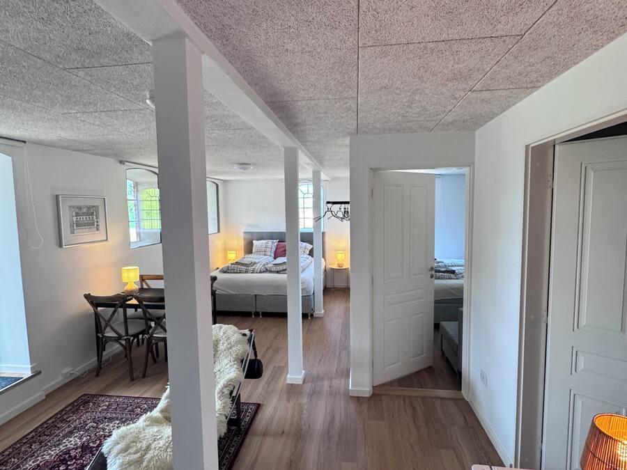 Um interior moderno com um corredor que leva a quartos, uma sala de jantar e uma sala de estar com sofá e tapete.