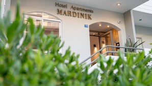 L’entrée de l’hôtel-résidence MARDINIK se fait par une porte vitrée, un escalier et une enseigne indiquant le numéro de chambre 74.