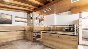 Eine moderne Küche mit Holzausstattung, einer Wand aus Naturstein und einem aufgehängten Hirschkopf.