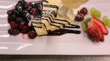 Un plato de postres con varias frutas y un chorrito de chocolate.