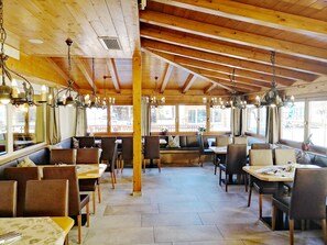 Restaurante con vigas de madera, candelabros y ventanas amplias que ofrecen vistas al exterior.