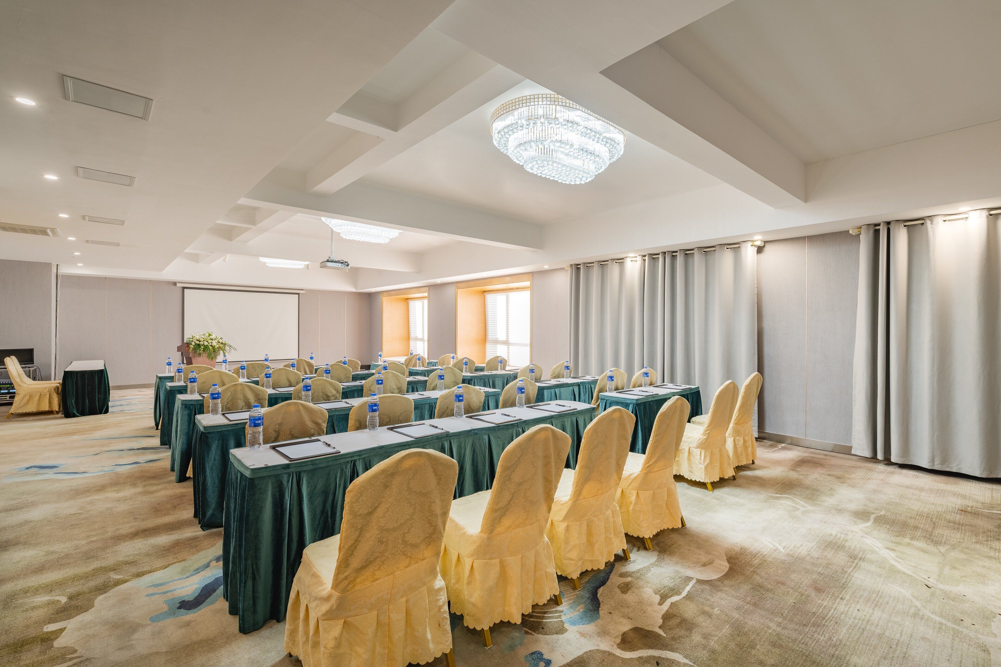 A conference room with long tables, chairs, and a chandelier.