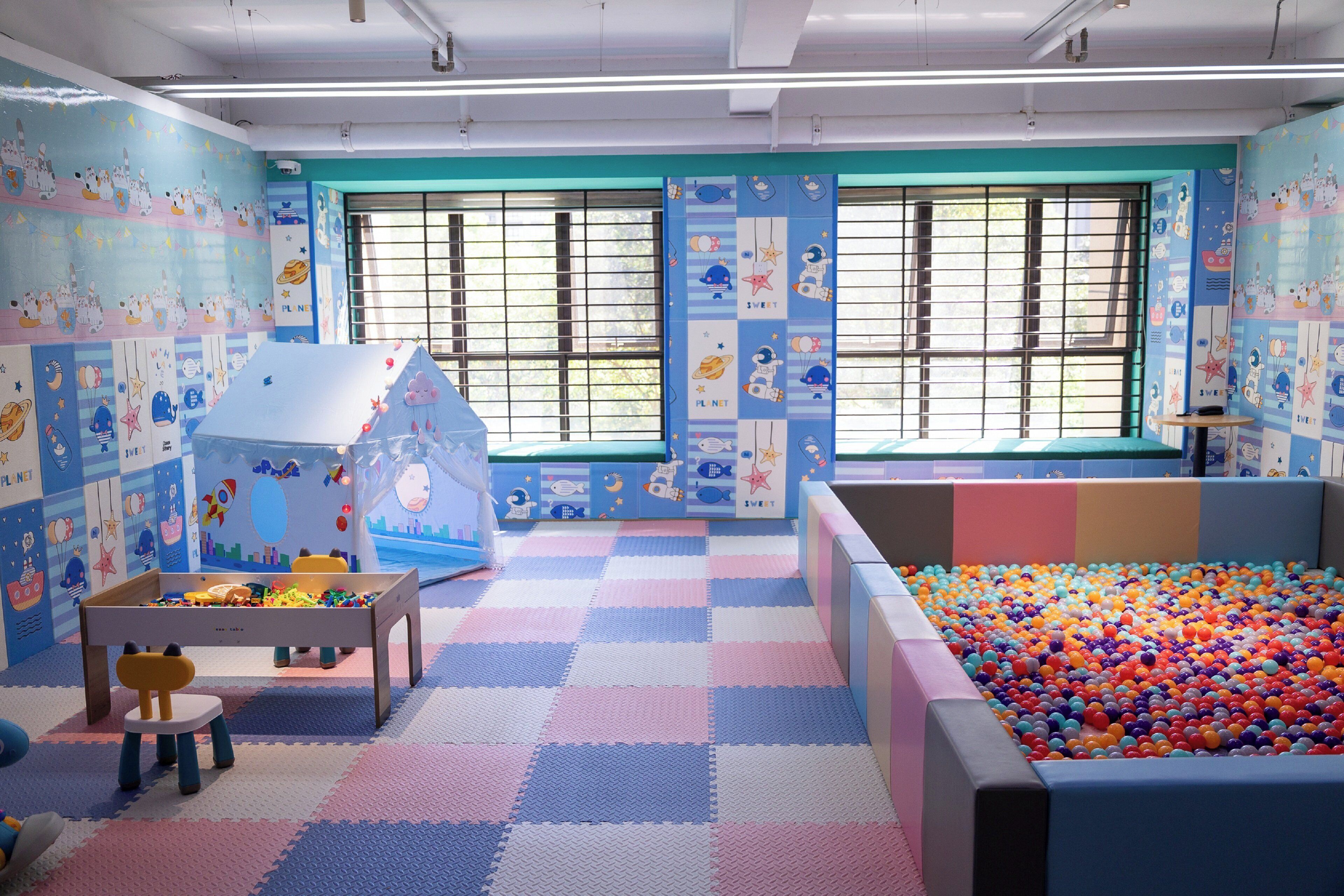 A children's playroom with a ball pit, a playhouse, and a table with toys.