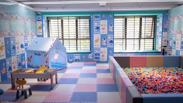 A children's playroom with a ball pit, a playhouse, and a table with toys.