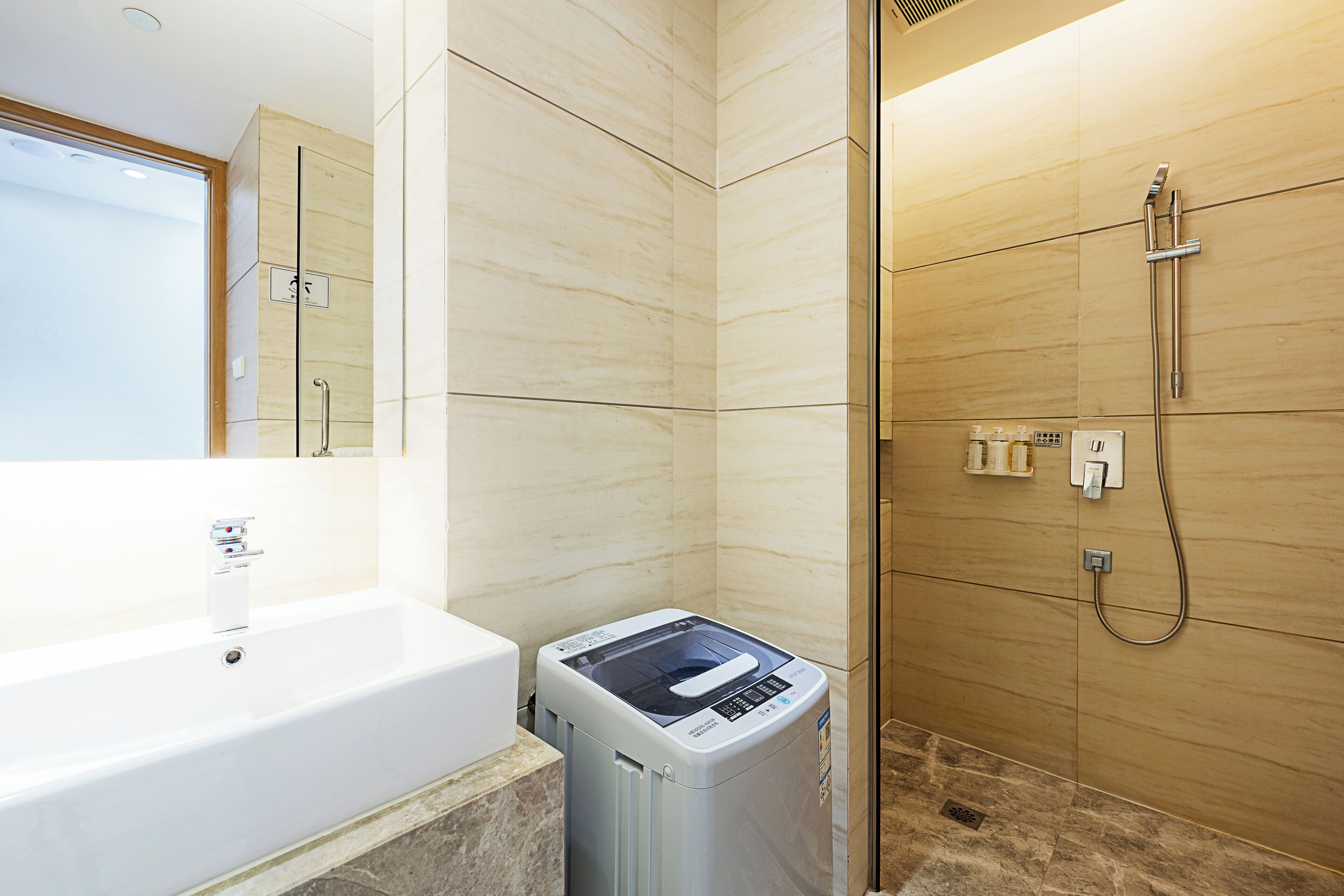 A modern bathroom with a white bathtub, a glass-enclosed shower, and a built-in washing machine.