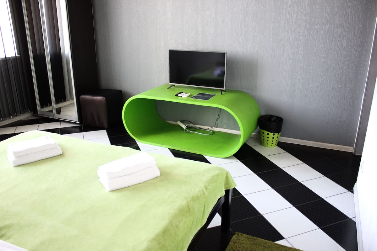 A room with a massage table, a green console with a TV, and a black and white checkered floor.