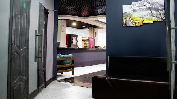 Un área de recepción con mostrador, zona de estar con banco y una obra de arte colgada en la pared.