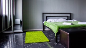 Una habitación de hotel moderna con una cama, una alfombra verde y un espejo grande.