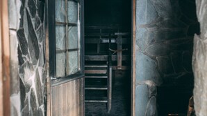 A narrow stone-walled corridor with a wooden door and a metal ladder. - Little Peak (Kuusamo)