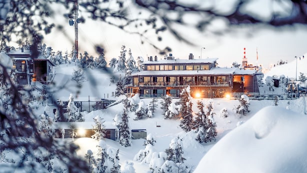 A multi-story building with a snow-covered roof and surrounding trees, likely a hotel or resort. - Little Peak (Kuusamo)