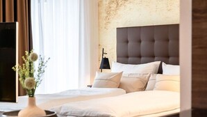 A neatly made bed with white linens, a dark headboard, and a bedside table with a vase of flowers. - H23 Boardinghotel (Stuttgart)