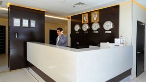 Un comptoir d’accueil avec des horloges indiquant l’heure à Tokyo, Londres, Koweït et New York.
