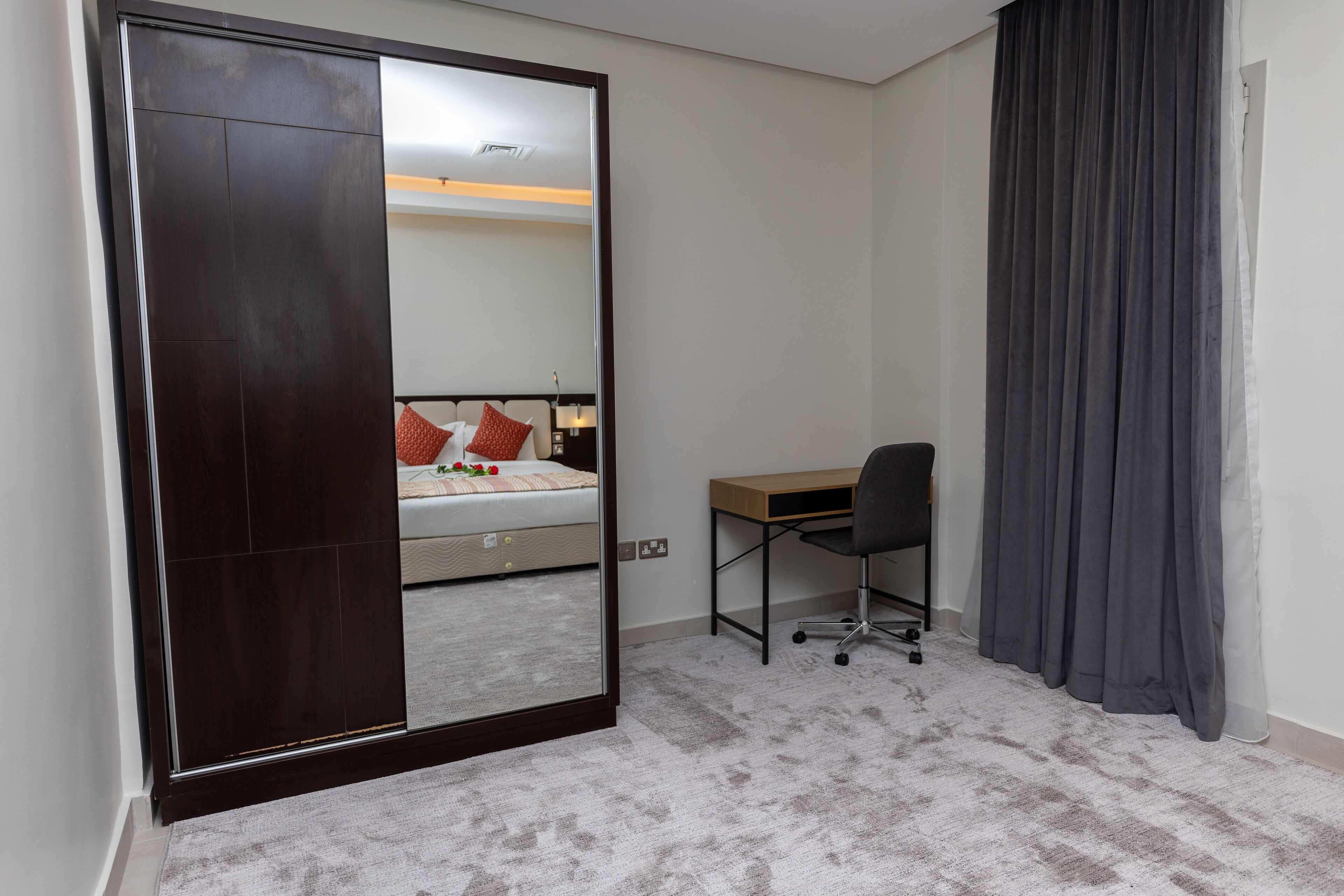 Un dormitorio con un espejo grande, una cama, un escritorio y una silla.