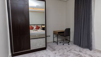 Un dormitorio con un espejo grande, una cama, un escritorio y una silla.