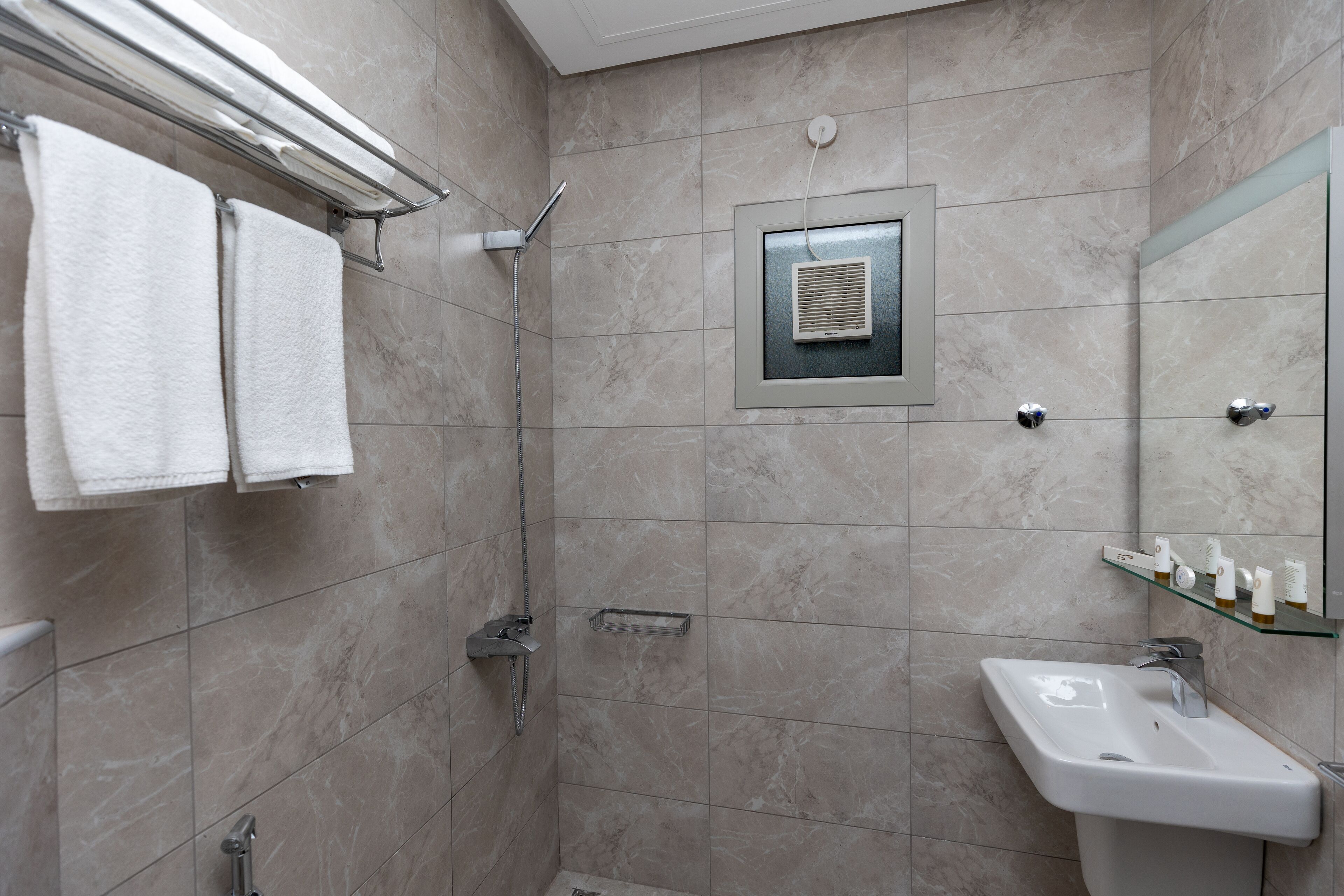 A modern bathroom with a shower, a sink, and a mirror.