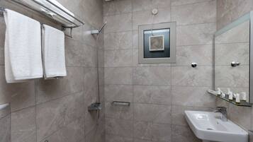 A modern bathroom with a shower, a sink, and a mirror.