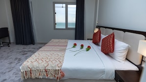 Une chambre d’hôtel avec un lit, une fenêtre, un bureau et une vue sur l’océan.