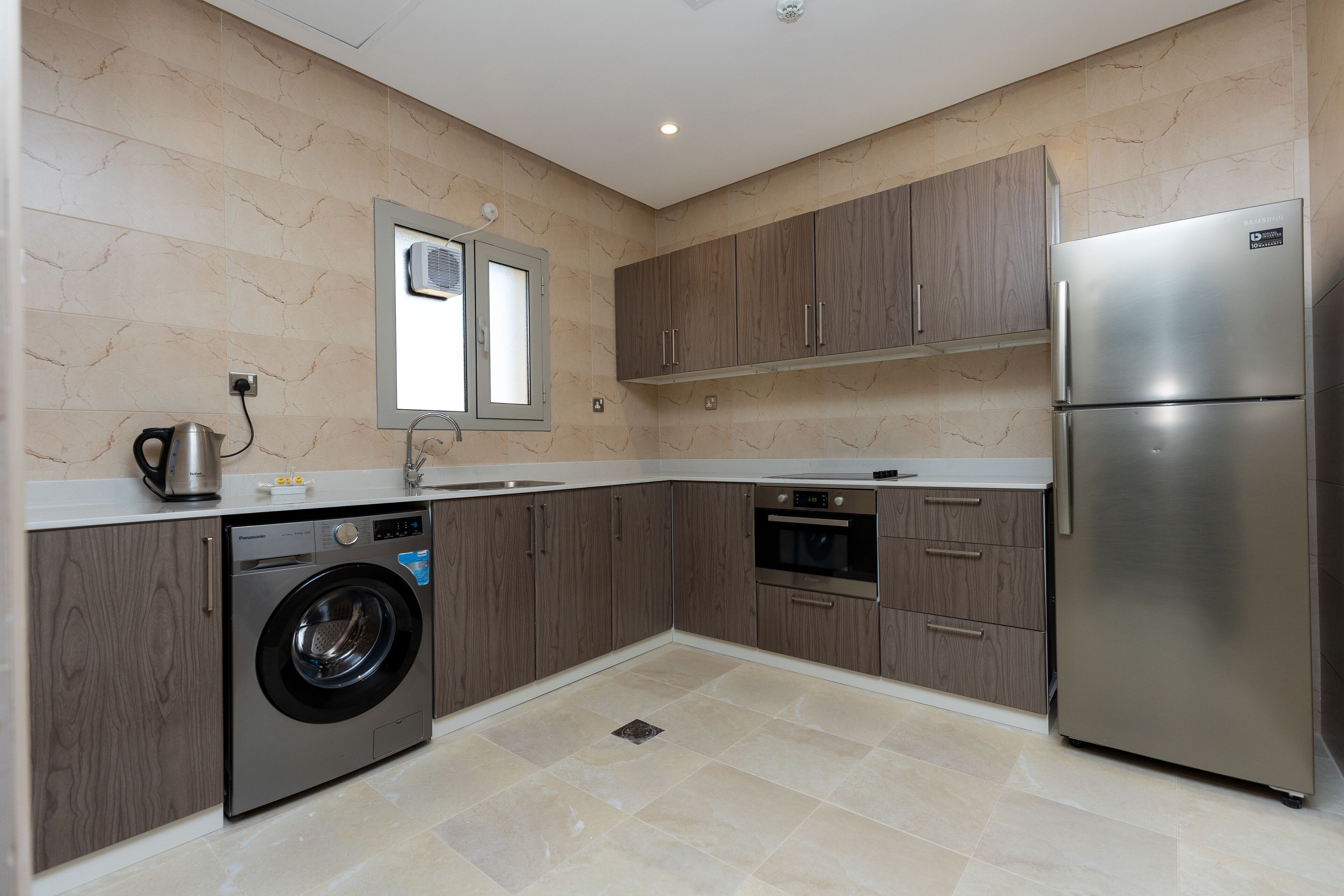 Una cocina moderna con refrigerador de acero inoxidable, horno empotrado y lavadora.