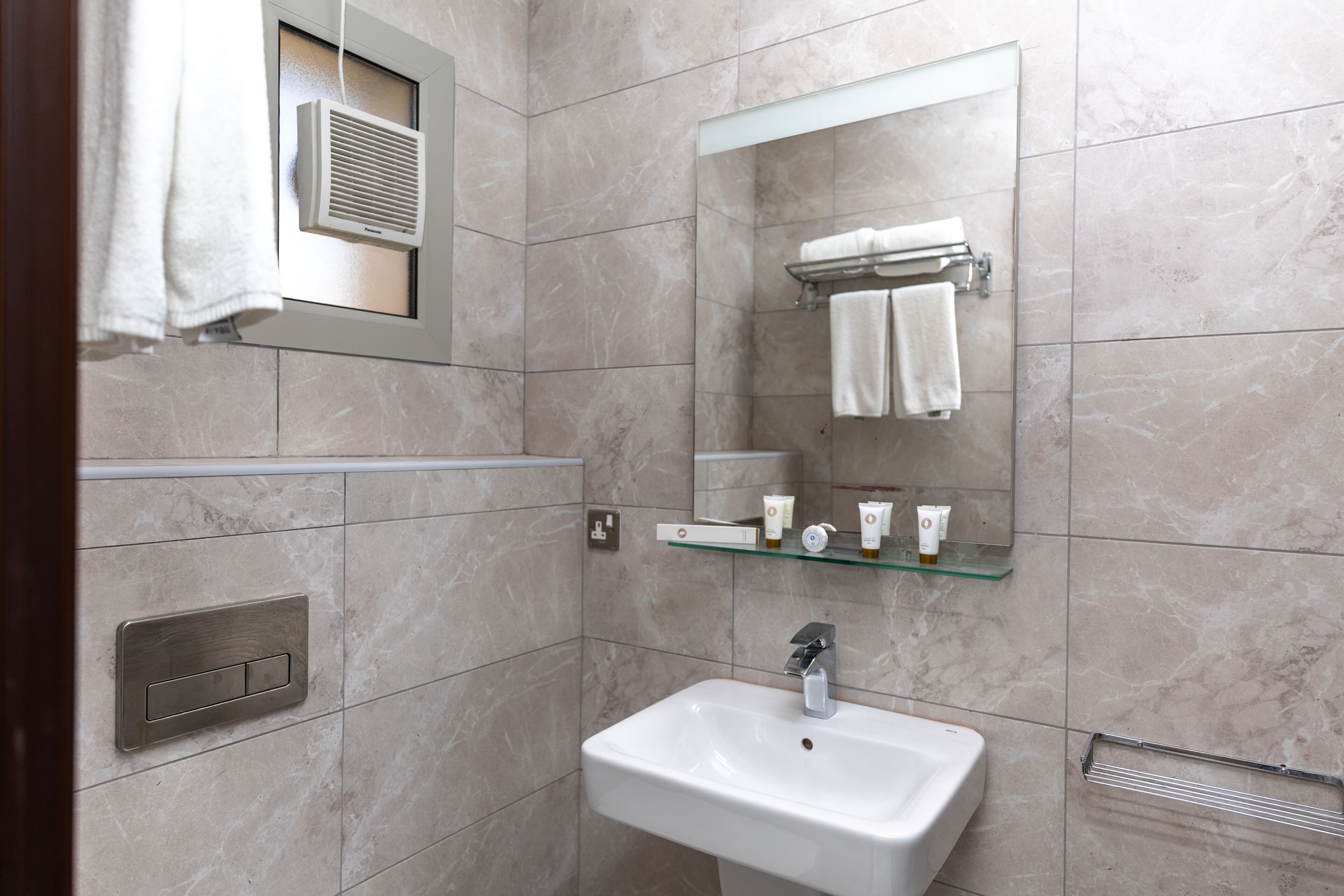 A bathroom with a white sink, a mirror, and a towel rack.
