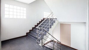 A modern staircase with metal railings and dark steps, leading to an upper floor in a bright, minimally furnished interior.