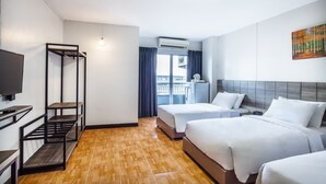 A hotel room with two beds, a TV, a balcony with a view, and an air conditioning unit.