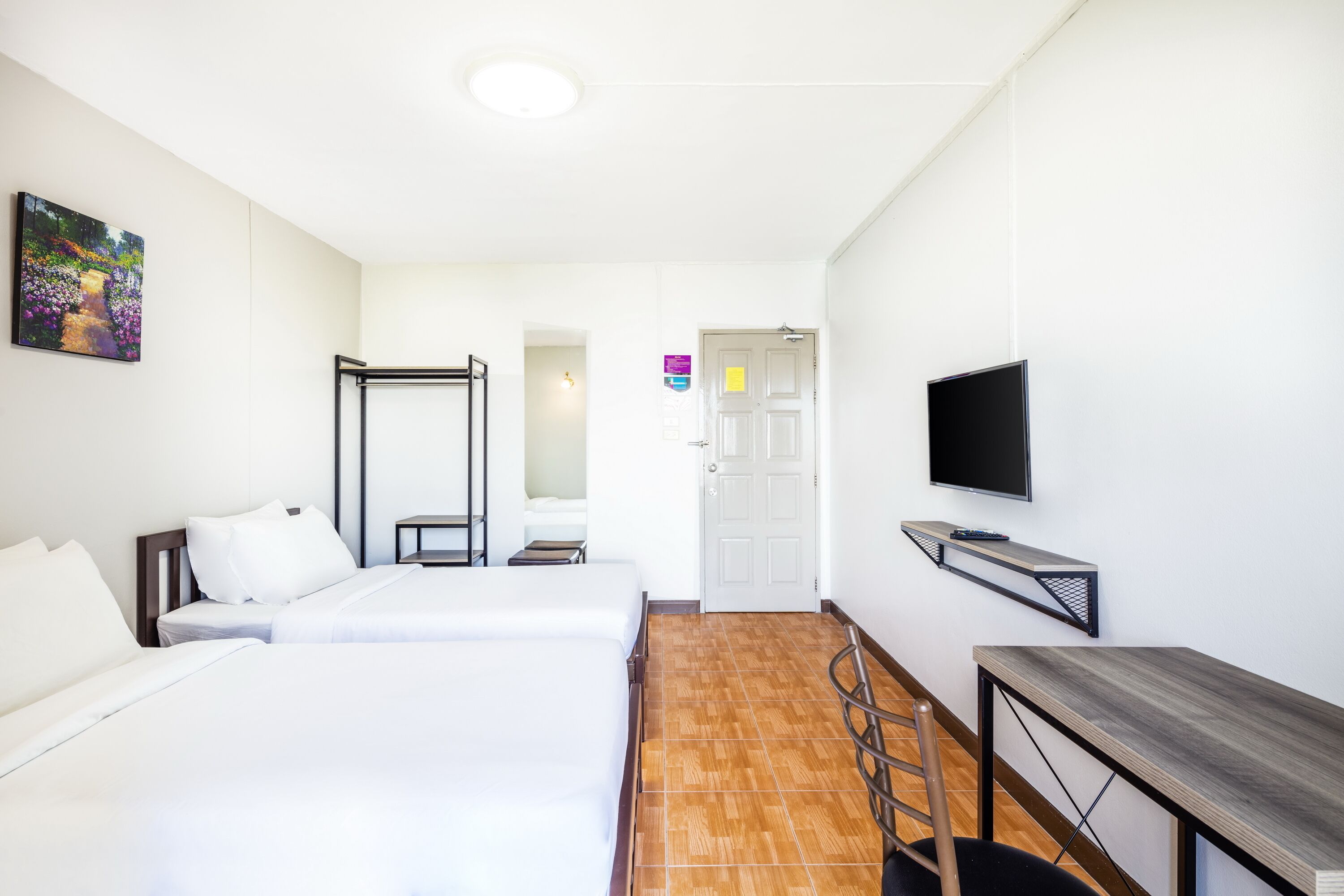 Ein Hotelzimmer mit zwei Betten, einem Schreibtisch, einem Fernseher und einer Badezimmertür.