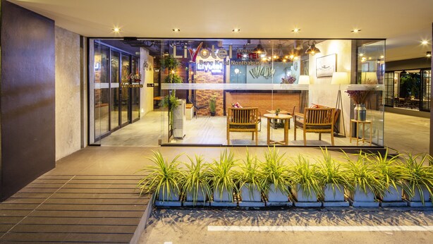 A modern hotel lobby with glass doors, a reception desk, and seating area.