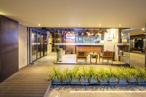 A modern hotel lobby with glass doors, a reception desk, and seating area.