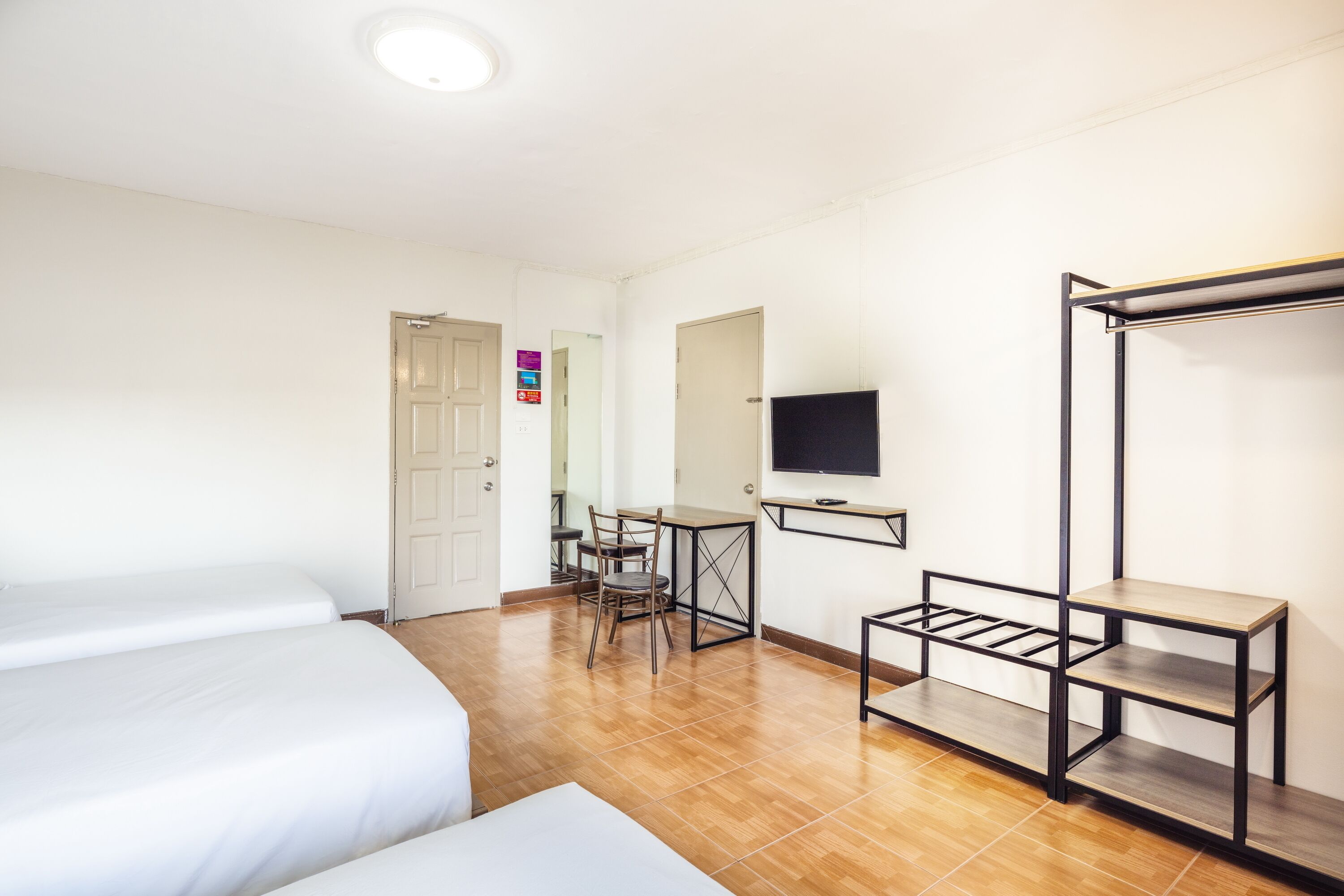Una camera d'albergo con due letti, una scrivania con sedia, una televisione e un armadio.