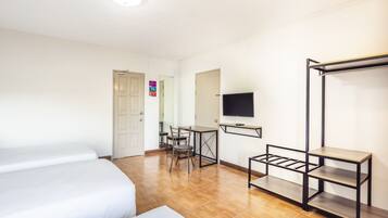 Una camera d'albergo con due letti, una scrivania con sedia, una televisione e un armadio.