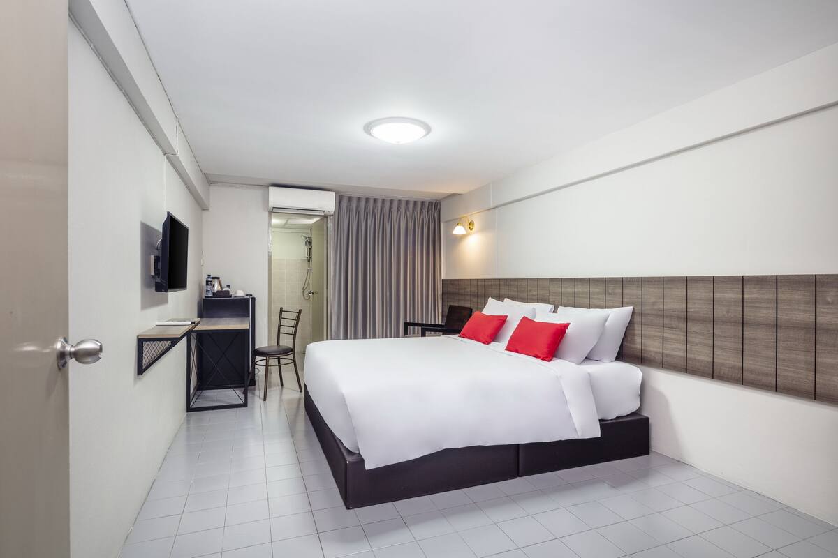 A modern hotel room with a large bed, a desk, and a television.