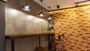 A modern interior with a brick wall, wooden bar counter, and black metal chairs. - Livotel Express Hotel Ramkhamhaeng 50  Bangkok (Bangkok)