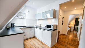 A modern kitchen with white cabinets, a microwave, and a kettle. - Rentplanet - Bulwary Słowackiego (Zakopane)