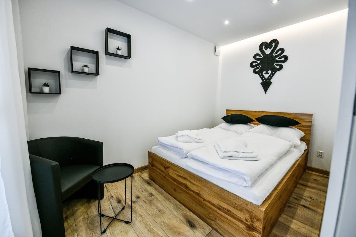 A modern bedroom with a wooden bed, a black chair, and a small round table.