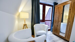 A room with a white sofa, a wooden table, a lamp, and a wooden wardrobe. - Rentplanet - Bulwary Słowackiego (Zakopane)