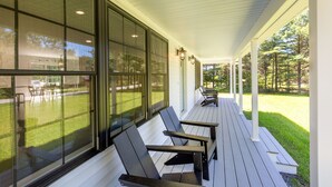 Ein überdachter Balkon mit Sitzgelegenheiten und großen Fenstern.