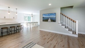 Eine geräumige Küche mit Holzboden, einem Essbereich mit Stühlen, einer Treppe und einem Bild an der Wand.