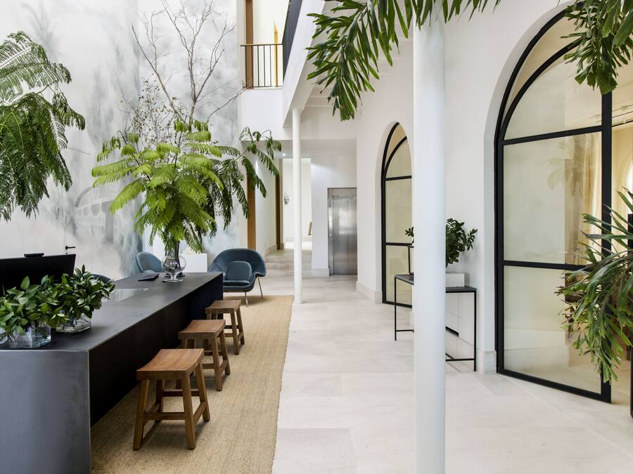Un espacio interior moderno con un mostrador de recepción amplio, varias zonas de estar y grandes ventanales que dejan entrar luz natural.