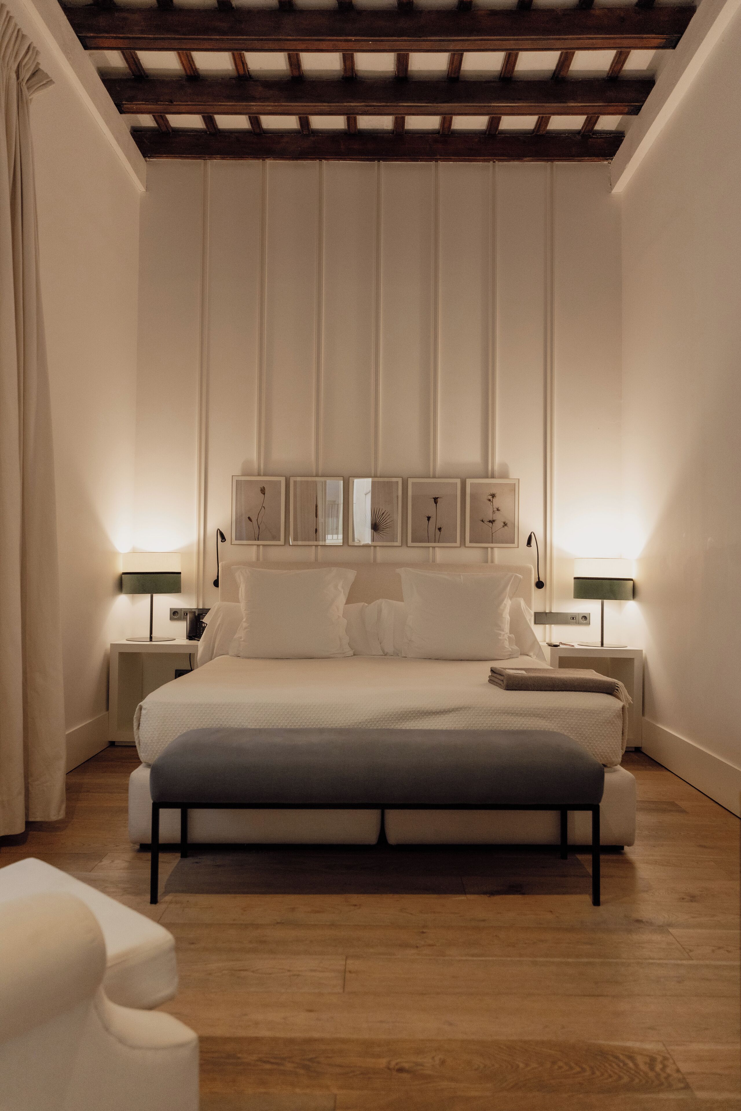 Une chambre moderne avec un grand lit, des tables de chevet avec des lampes et un plafond en bois.