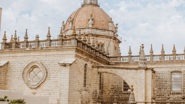 Uma área de piscina com vista para um edifício histórico com cúpula e arquitetura elaborada.