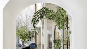 Um interior moderno com um arco central, um balcão de recepção e plantas em vasos.