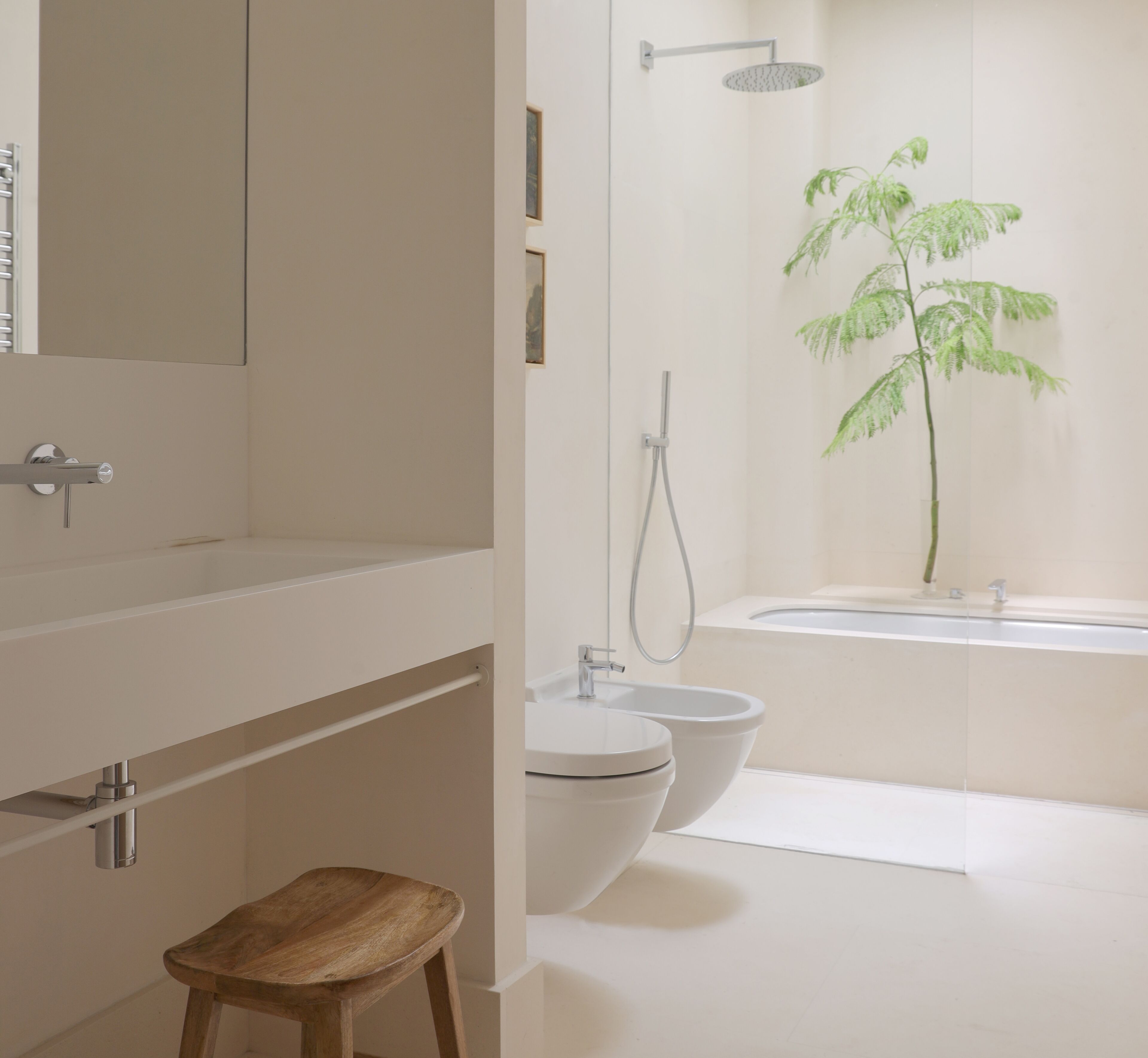 Une salle de bain moderne équipée d’une douche, de deux toilettes, d’un lavabo et d’un tabouret en bois.