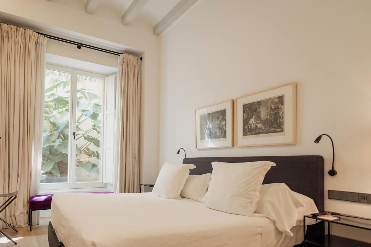 Une chambre moderne avec un grand lit, un bureau et deux tableaux encadrés accrochés au mur.