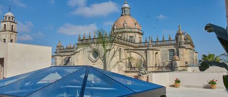 A modern glass-roofed structure adjacent to a historic building with ornate architecture and a dome.