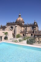 Edificio histórico con una cúpula grande y arquitectura ornamentada, junto a una piscina.