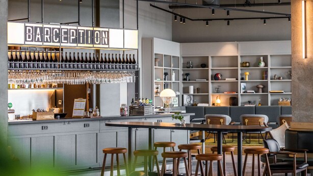 A modern bar area with a sign reading "BARCEPTION," featuring a wine rack, bar stools, and a seating area with tables and chairs. - Comfort Hotel Copenhagen Airport (Kastrup)