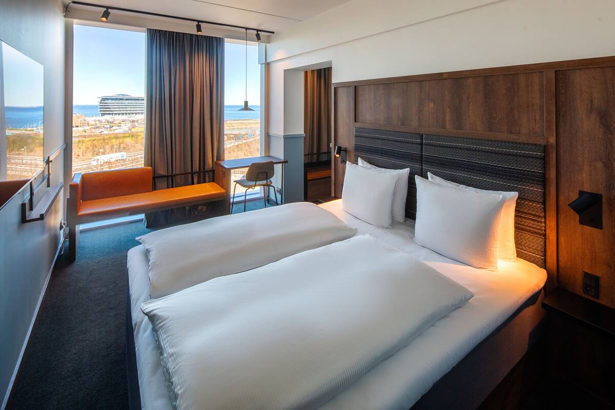 A hotel room with a large bed, a desk, and a view of the beach.