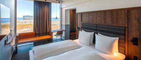 A hotel room with a large bed, a desk, and a view of the beach.