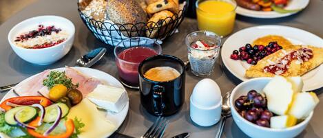 A breakfast buffet with various dishes including croissants, eggs, and fresh fruits.