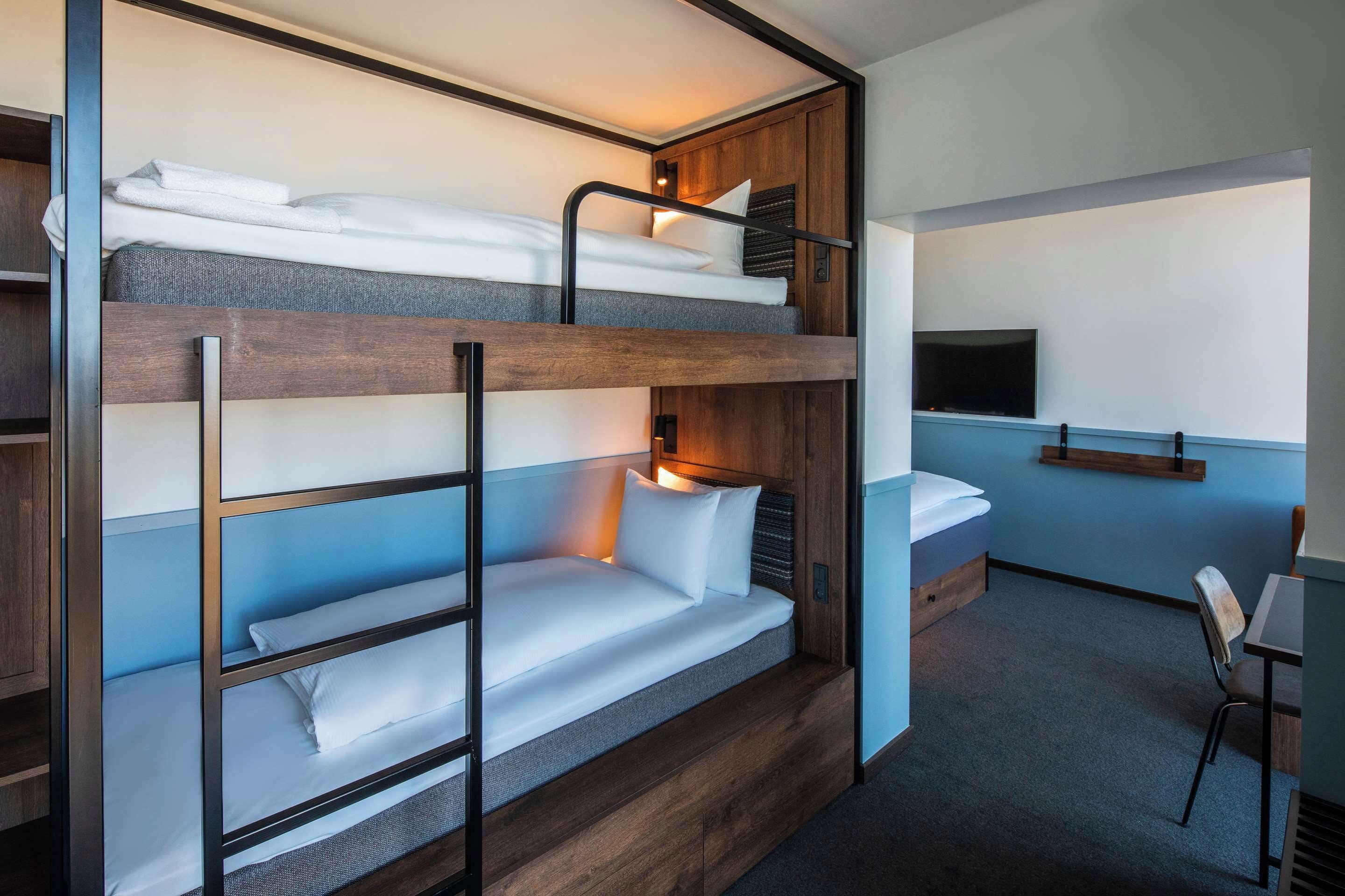 A bunk bed room with a desk and a TV.